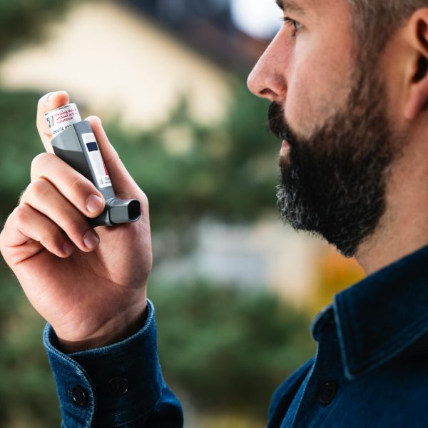 pexels-photo-30425664-30425664 Adult man uses inhaler outdoors for asthma relief, focusing on respiratory health.