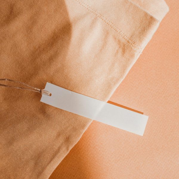 pexels-photo-8148725-8148725 Close-up of a beige fabric with a blank white tag, perfect for branding or mockup.
